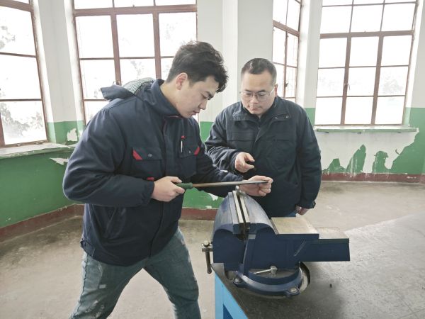 技術(shù)能手——郭峰峰正在指導青工張帆鉗工操作技能.jpg